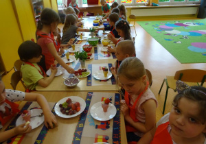 Dzieci nakładają owoce do wafelków.